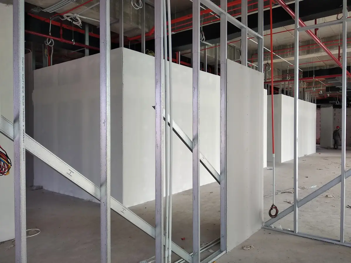 Crew installing drywall board on a steel stud wall